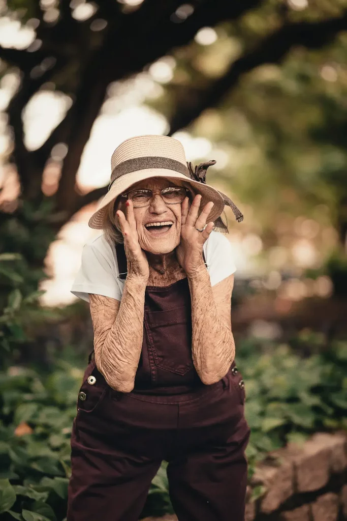 Fröhliche ältere Dame mit Hut in Iserlohn lacht herzlich.